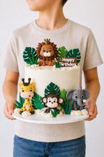 Animal jungle birthday cake with animal figurines and green leaves