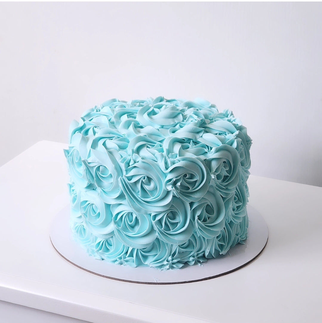 Light blue rosette cake on a white surface with a white background