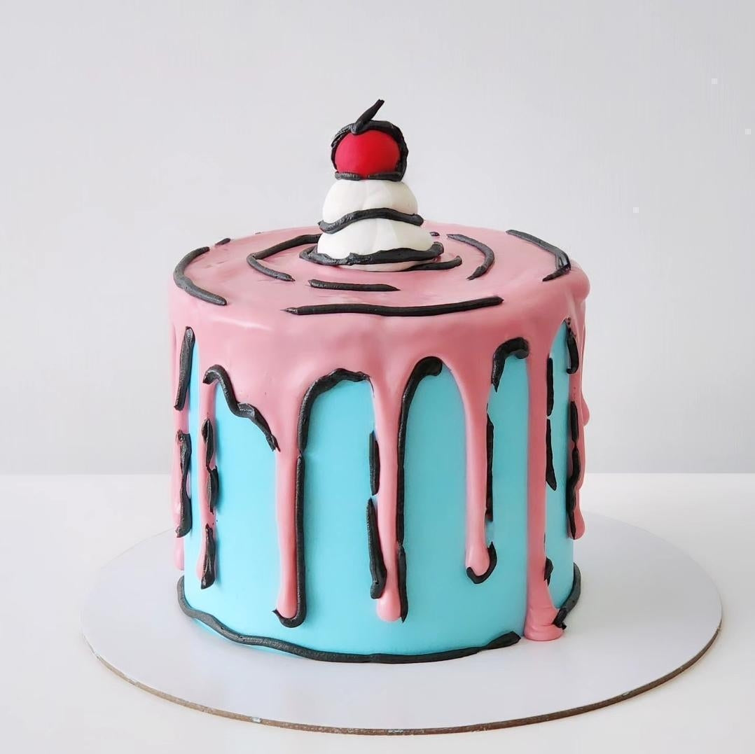 A multi-layered cake with a cartoonish design, featuring a white frosting layer with a red apple on top, and pink chocolate drips designed to resemble a comet or splash.