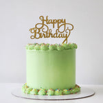 A green party cake with 'Happy Birthday' written in gold letters on top, decorated with a layer of multicolored sprinkles.