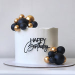 White birthday cake with black and gold balloons on a white background sydney 