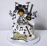 A themed birthday cake decorated with musical notes, a guitar, and a drum set on top, with 'Happy Birthday' text visible.