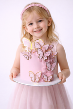 Young girl holding a cake with butterfly decorations on a white background