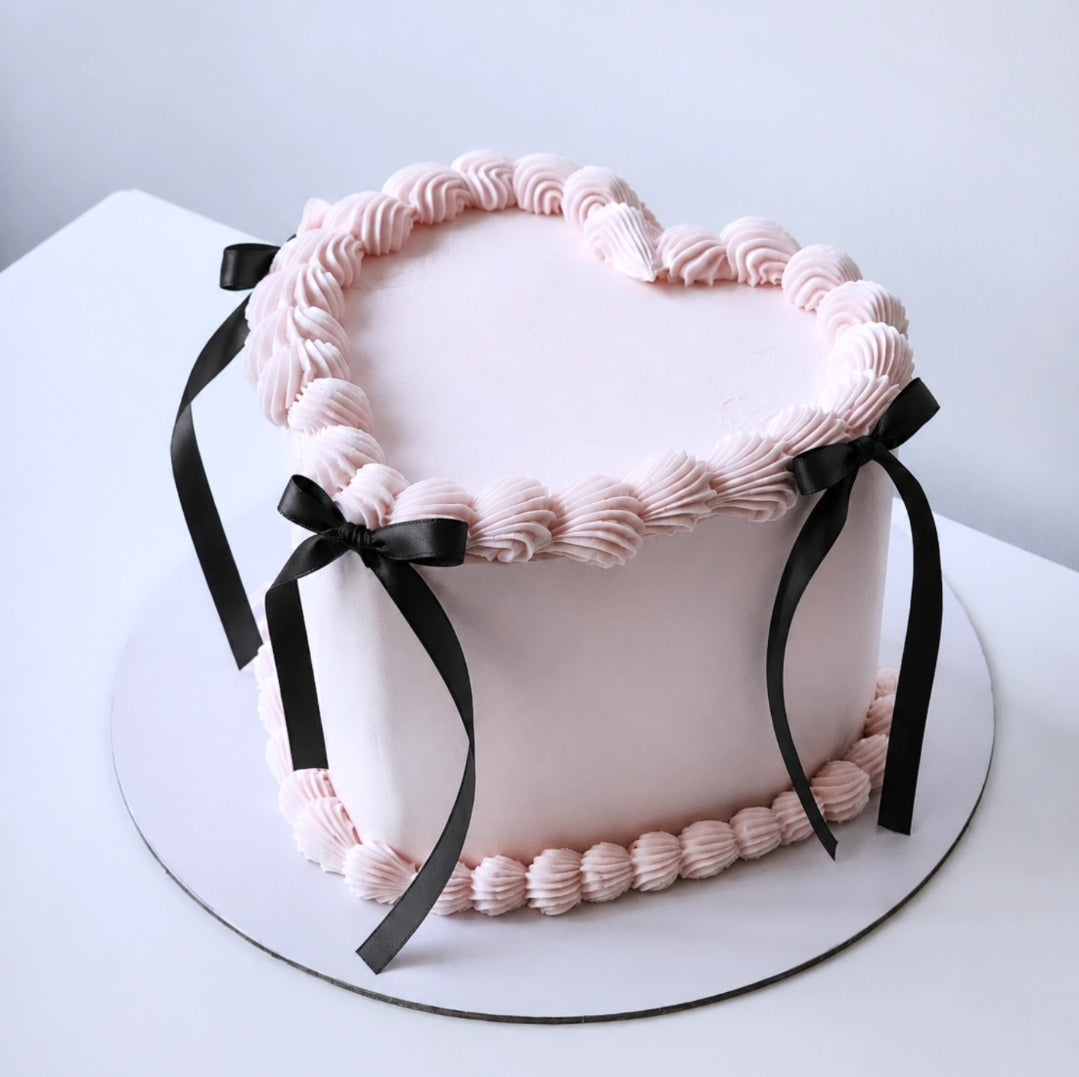 Pink cake with vintage piping and black ribbons 