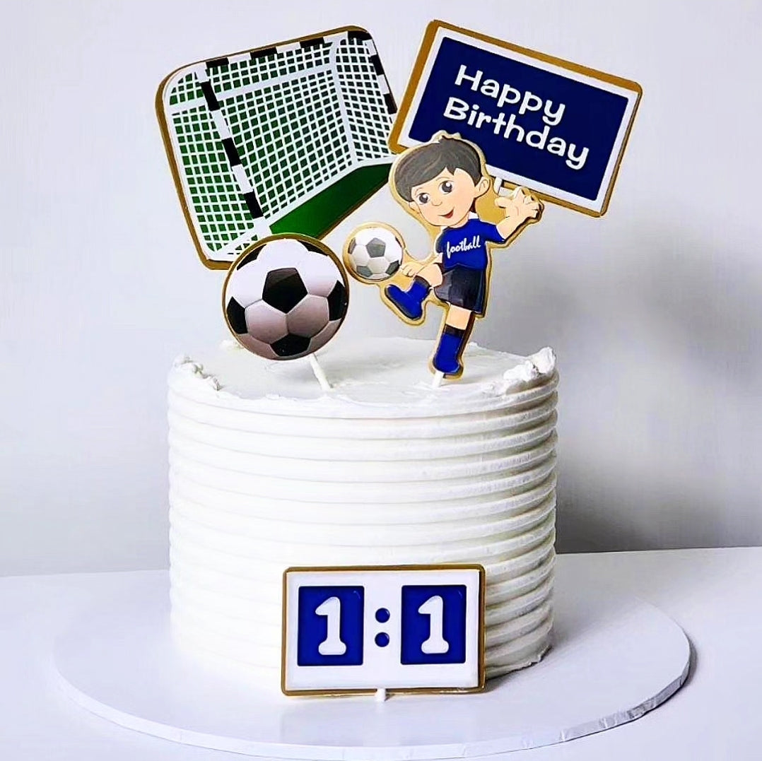 A soccer-themed birthday cake with a green and white soccer ball, a cartoonish soccer player, and a 'Happy Birthday' sign.