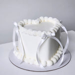 White cake with decorative ribbon on a plain background