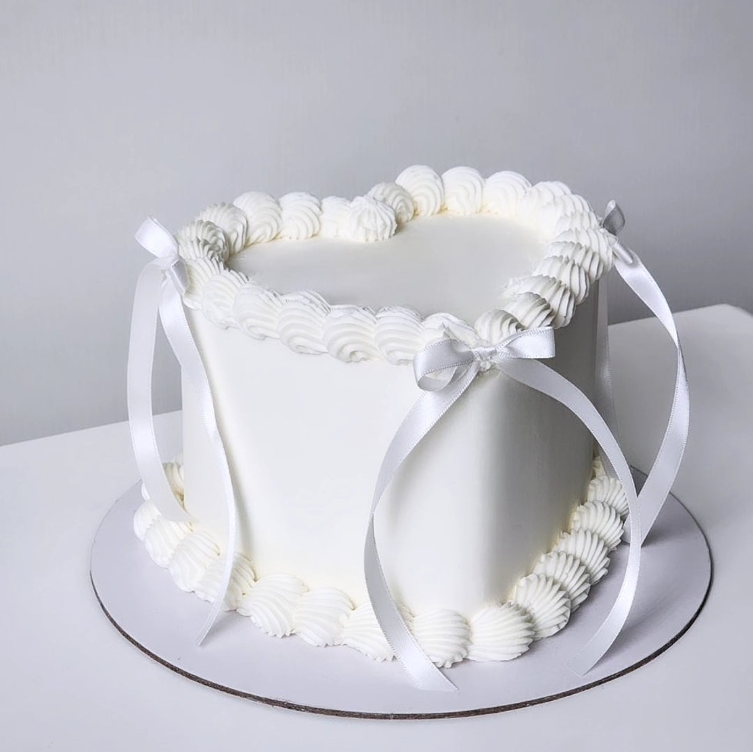 White cake with decorative ribbon on a plain background