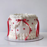 White cake with red ribbons and heart decorations on a white background