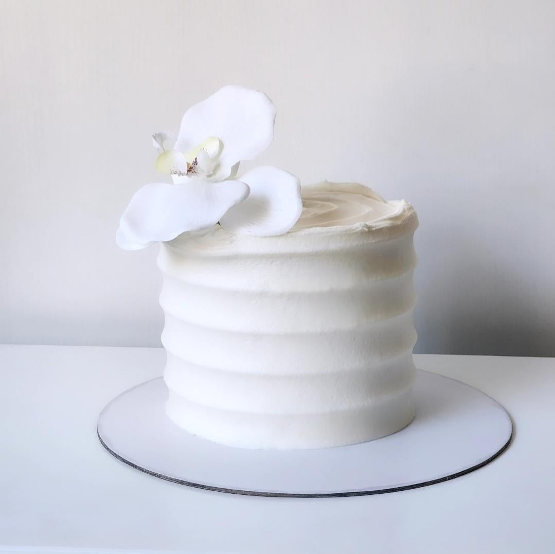 White cake with a single white flower on a white background