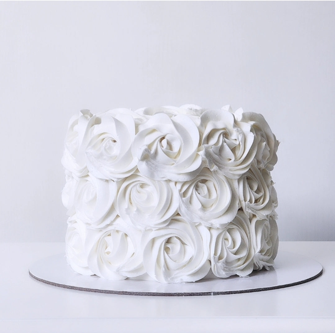 White cake with rose-shaped frosting on a white background