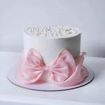 White cake with a pink bow and pearl decorations 