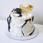Graduation-themed cake with a topper and black ribbons , sydney
