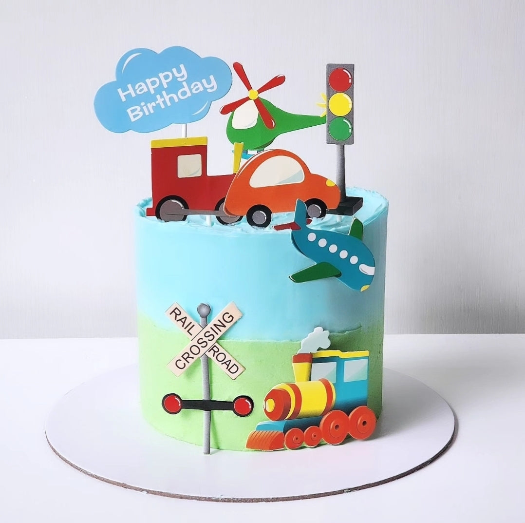 A birthday cake decorated with playfull car, train, and plane, with birthday greetings and toy vehicles on top.