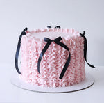 Pink ruffled cake with black ribbons 