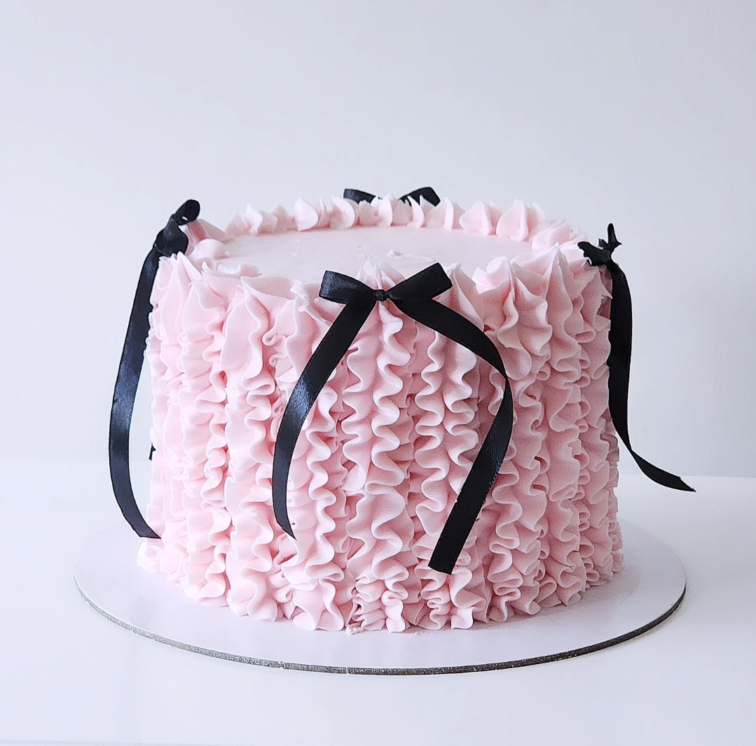 Pink ruffled cake with black ribbons 