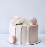 Delicate cake with pink macarons and white flowers 