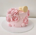 A pink swirled cake decorated with creamy pink frosting and a spiral design, topped with a few macarons.