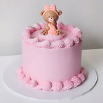 A pink teddy-themed cake, surrounded by pink buttercream decorations 
